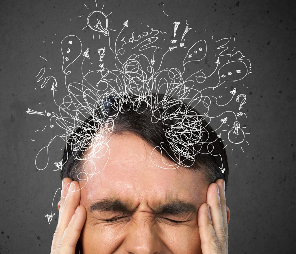 Man with hands on head with lots going on in his mind