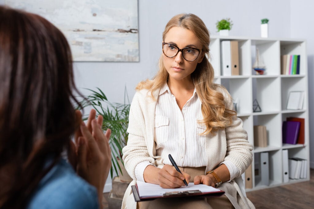 professional woman with blond hair taking notes during a session